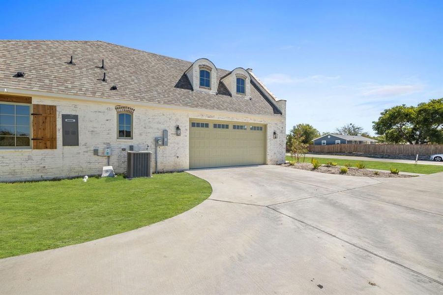 View of front facade featuring a front yard, a garage, and central air condition unit