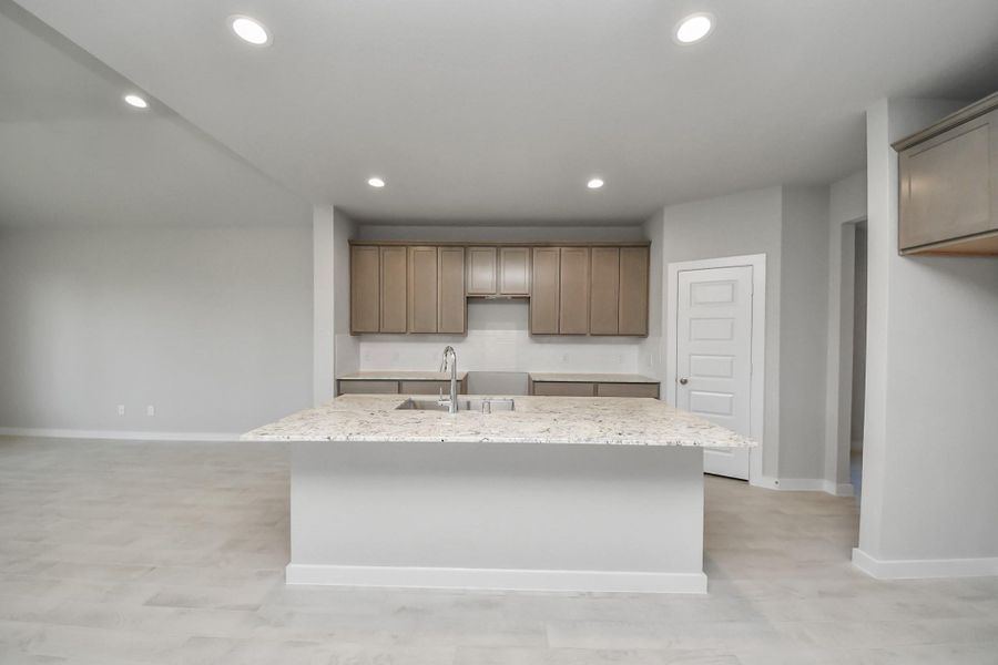 Culinary haven, featuring granite countertops, a tile backsplash, stainless steel appliances (to be installed), and 42” upper cabinets. Sample photo of completed home with similar floor plan. Actual colors and selections may vary.