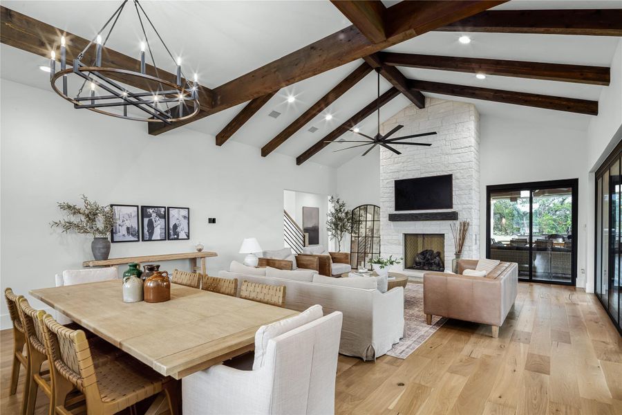 Dining area with high vaulted ceiling, a fireplace, light hardwood / wood-style floors, and beam ceiling