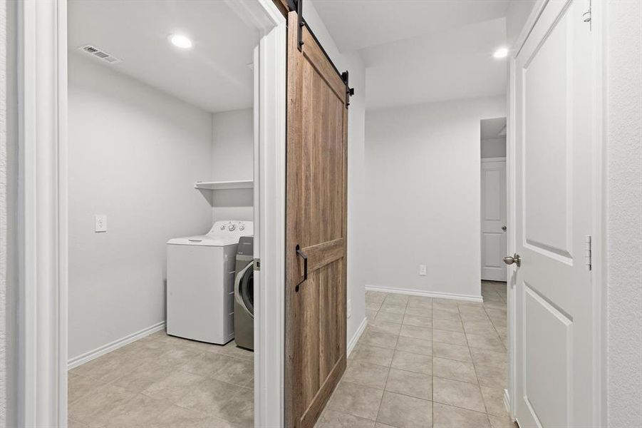 View of laundry, barn door and hall
