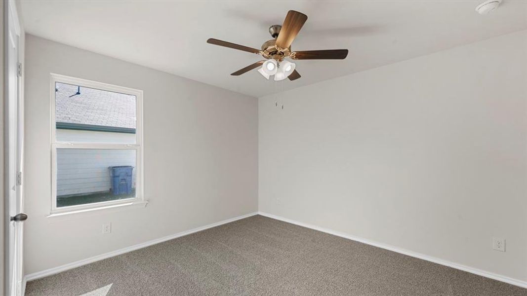 Neutral-toned room featuring a single window, a ceiling fan with integrated lighting, wall-to-wall carpeting, and white trim Neutral-toned room featuring a single window, a ceiling fan with integrated lighting, wall-to-wall carpeting, and white trim
