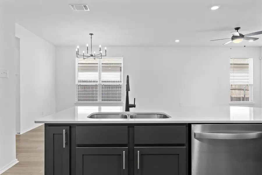 Kitchen featuring stainless steel dishwasher, light wood-type flooring, decorative light fixtures, recessed lighting, and light stone counters