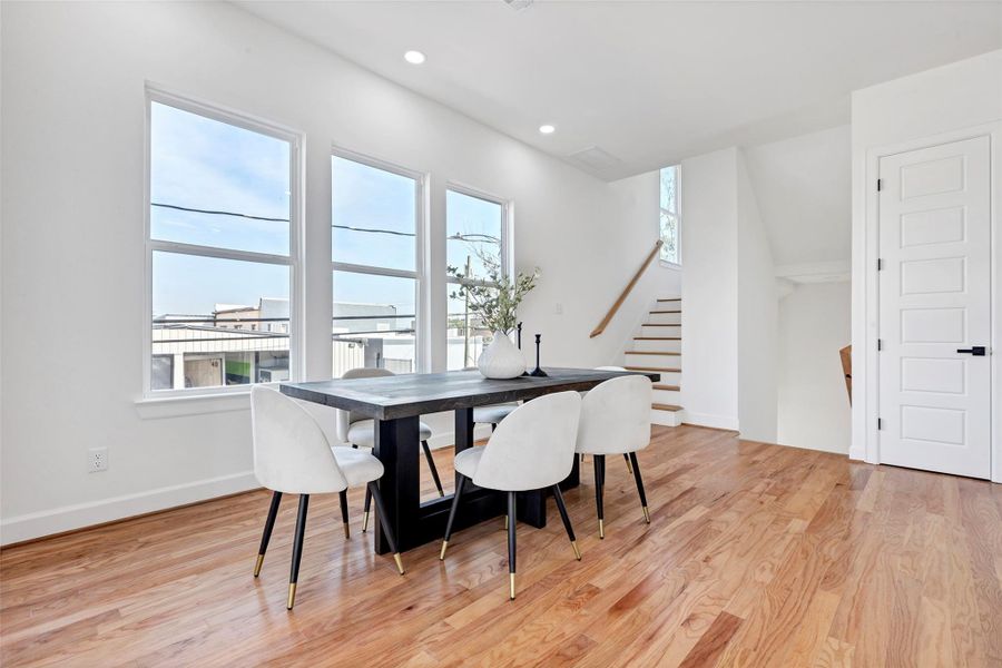 This dining area is bathed in natural light from large windows, with a staircase in the corner leading up to the third floor. (Representation of previously built homes. Actual colors and finishes will vary.) This dining area is bathed in natural light from large windows, with a staircase in the corner leading up to the third floor. (Representation of previously built homes. Actual colors and finishes will vary.)