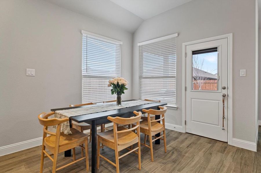 Dining space featuring dark wood-type flooring, lofted ceiling, and a wealth of natural light