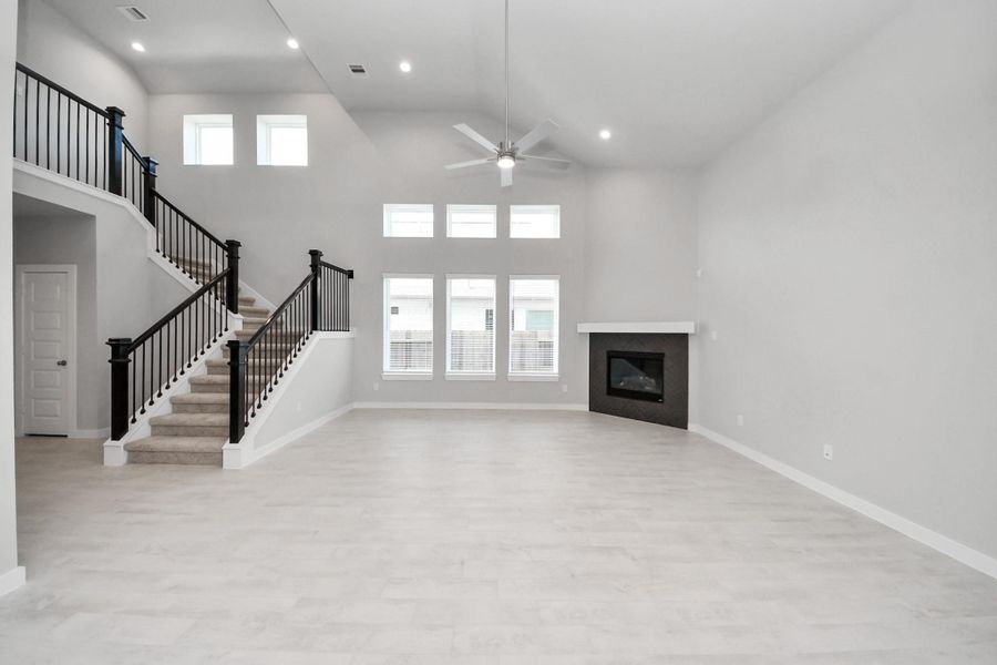 Welcome family and guests to your charming living room! With its high ceilings, recessed lighting, ceiling fan, custom paint, beautiful flooring, and large windows that let in abundant natural light, this room is perfect for gatherings.