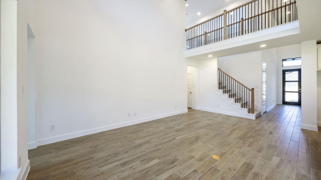 Unfurnished living room featuring a high ceiling, stairs, wood finished floors, and recessed lighting