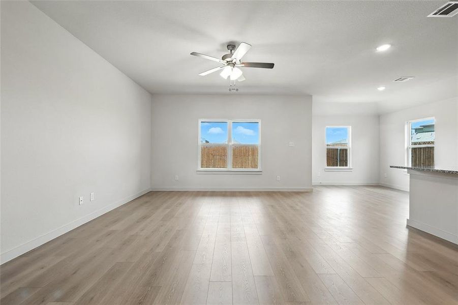 Unfurnished living room with light wood-style flooring, ceiling fan, and recessed lighting Unfurnished living room with light wood-style flooring, ceiling fan, and recessed lighting