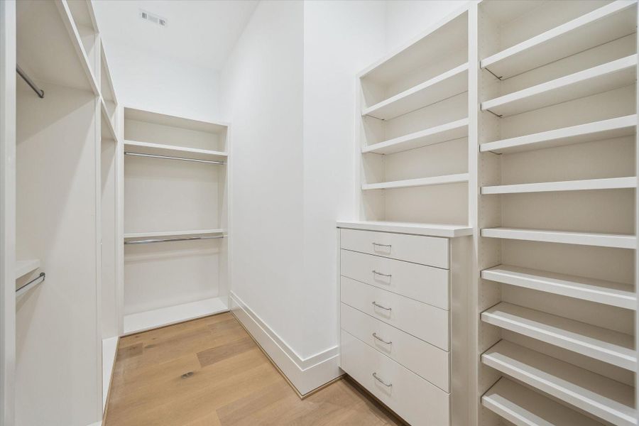 Walk-in closet for the secondary bedrooms, equipped with extensive custom built-ins, drawers, and generous storage space.