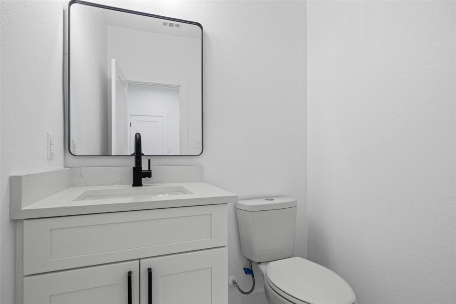 Bathroom vanity featuring a rectangular undermount sink with a matte black faucet, quartz-finish countertop, and white shaker-style cabinetry with black hardware Bathroom vanity featuring a rectangular undermount sink with a matte black faucet, quartz-finish countertop, and white shaker-style cabinetry with black hardware