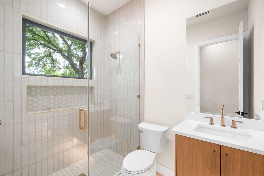 Modern bathroom featuring a glass-enclosed shower with vertical tile, a recessed shower niche, and a window for natural light