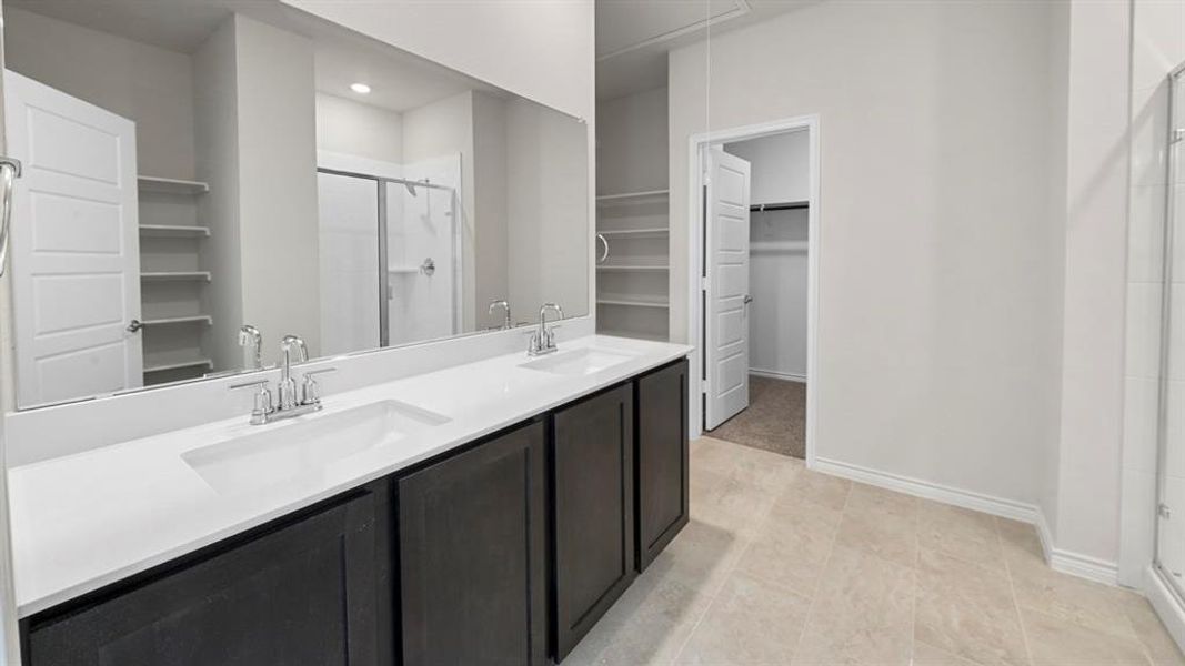 Bathroom featuring a double vanity with dark wood-finish cabinetry and white countertops Bathroom featuring a double vanity with dark wood-finish cabinetry and white countertops