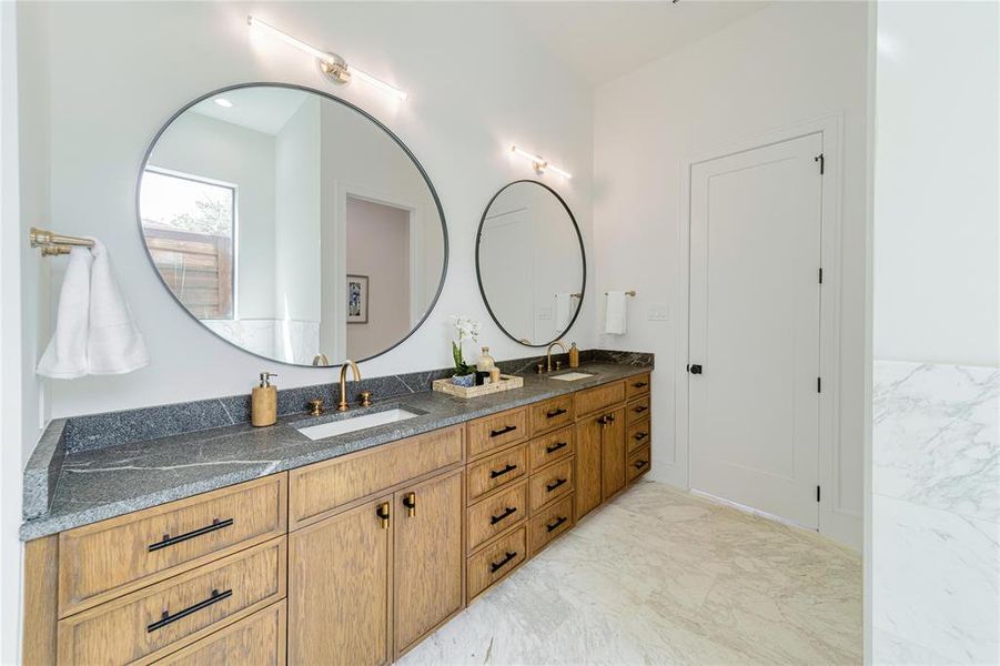 Full bathroom featuring double vanity and light marble finish flooring