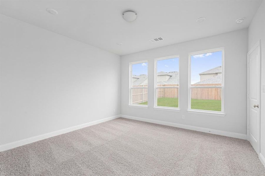 Carpeted empty room featuring baseboards, visible vents, and a healthy amount of sunlight