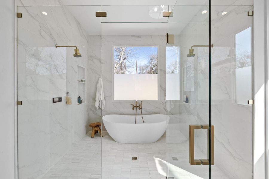 Bathroom with a marble finish shower and a freestanding tub