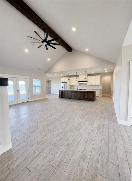 Expansive open-concept living space featuring a vaulted ceiling with exposed beam, recessed lighting, and a modern ceiling fan Expansive open-concept living space featuring a vaulted ceiling with exposed beam, recessed lighting, and a modern ceiling fan