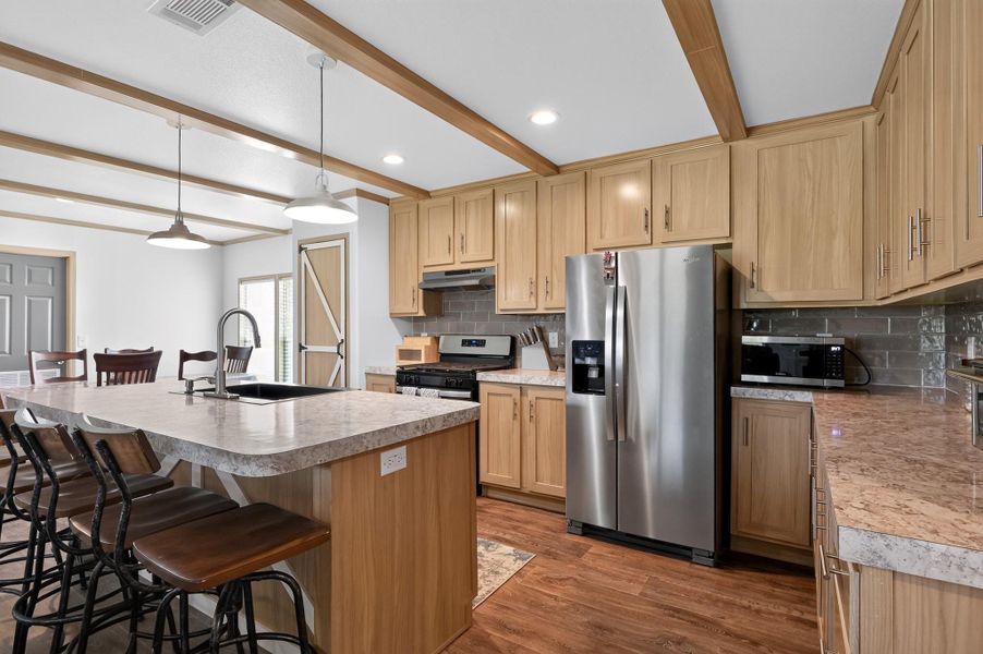 A well-appointed kitchen features wood-beamed ceilings, durable laminate countertops, and modern stainless steel appliances.