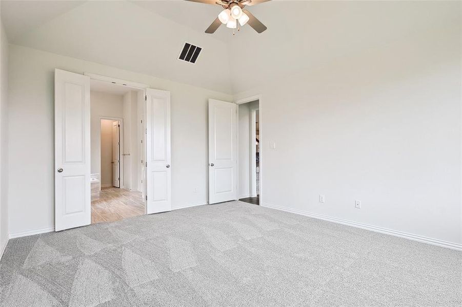 Unfurnished bedroom featuring ceiling fan, light carpet, and high vaulted ceiling