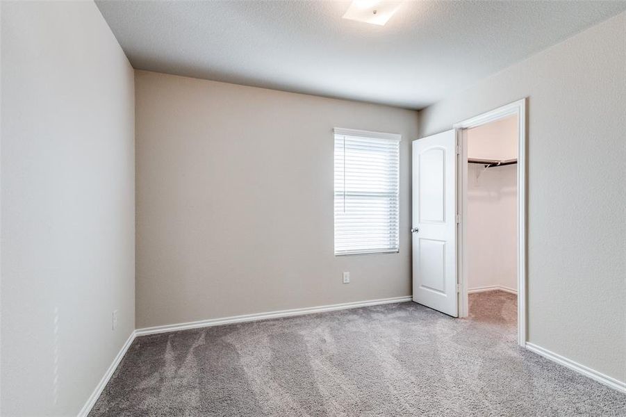 Unfurnished bedroom with carpet, a spacious closet, and a closet