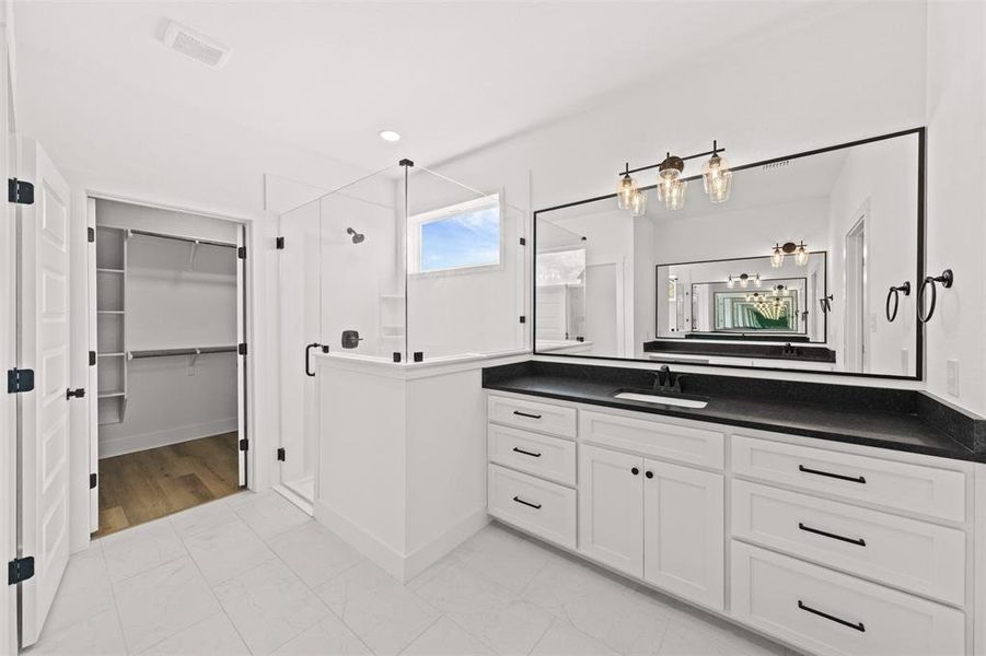 Bathroom with vanity, a shower stall, a walk in closet, and light marble finish floors