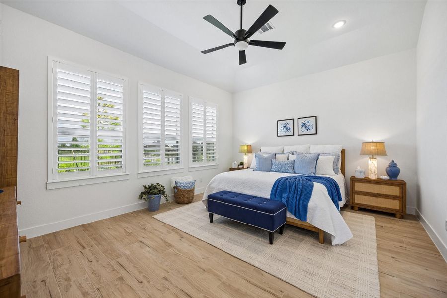 Spacious primary retreat featuring beautiful scenic views, custom plantation shutters, and upgraded wood-plank  tile flooring. This light-filled room offers an expansive layout perfect for accommodating oversized furniture.