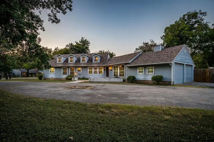 Cape cod house with asphalt driveway, an attached garage, a chimney, a front lawn, and a patio Cape cod house with asphalt driveway, an attached garage, a chimney, a front lawn, and a patio