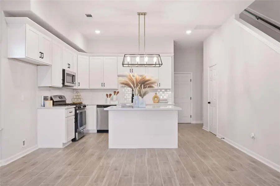 Spacious kitchen features upgraded cabinetry, crown molding, quartz countertops, stainless steel appliances, and a center island with pendant lights and bar-top seating. From a previous project with a similar floor plan Spacious kitchen features upgraded cabinetry, crown molding, quartz countertops, stainless steel appliances, and a center island with pendant lights and bar-top seating. From a previous project with a similar floor plan