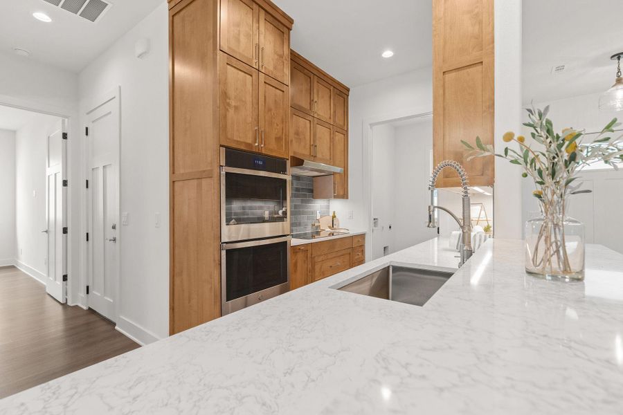 Kitchen featuring stainless steel double oven, a sink, light stone countertops, backsplash, and recessed lighting Kitchen featuring stainless steel double oven, a sink, light stone countertops, backsplash, and recessed lighting