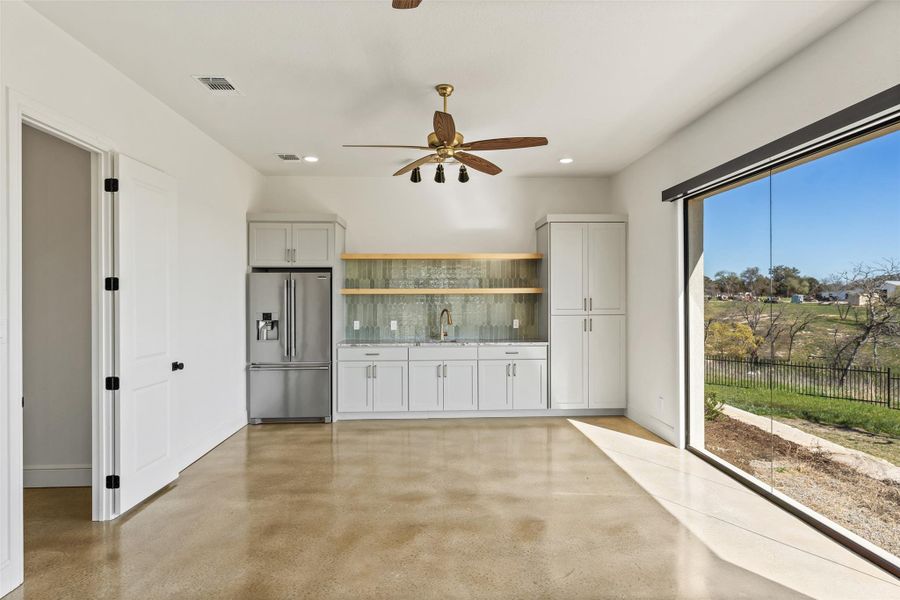 Kitchen featuring a ceiling fan, visible vents, a sink, high quality fridge, and tasteful backsplash