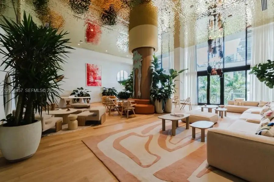 Common area featuring a textured gold-finish ceiling, floor-to-ceiling windows, wide-plank wood flooring, and a central architectural pillar Common area featuring a textured gold-finish ceiling, floor-to-ceiling windows, wide-plank wood flooring, and a central architectural pillar