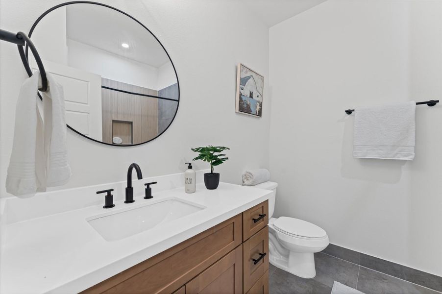 This secondary bathroom on the second floor is designed to serve two adjacent bedrooms with both style and functionality. It offers ample space for shared use, while the tub-shower combo provides versatility for quick rinses or relaxing soaks. The space is elevated by contemporary finishes and sleek tilework, creating a clean, modern aesthetic that feels both fresh and refined.