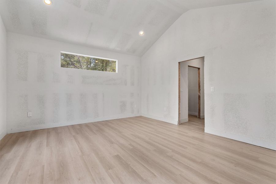 Empty room featuring vaulted ceiling, light wood-style flooring, and recessed lighting Empty room featuring vaulted ceiling, light wood-style flooring, and recessed lighting