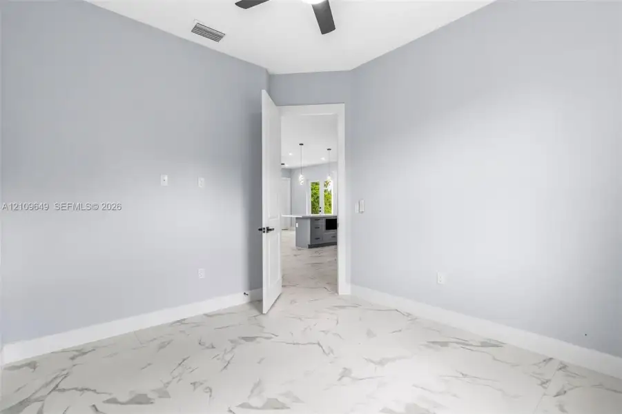 Room featuring large-format tile flooring with a veined pattern, neutral wall paint, and a ceiling-mounted fan