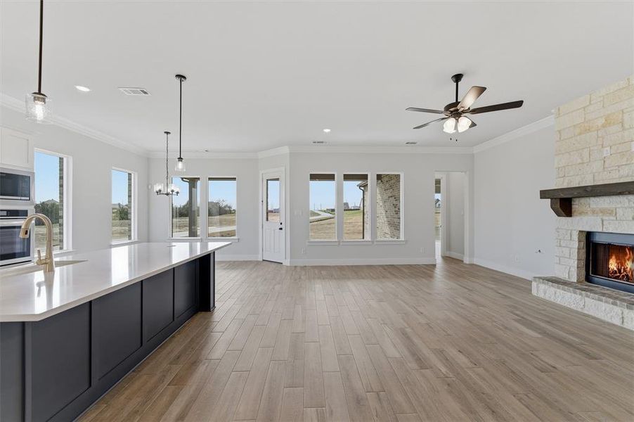 Kitchen featuring a stone fireplace, open floor plan, light wood-type flooring, a spacious island, and stainless steel appliances