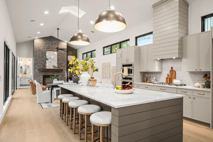 Kitchen with a skylight, a fireplace, a center island with sink, gray cabinets, and light wood-type flooring