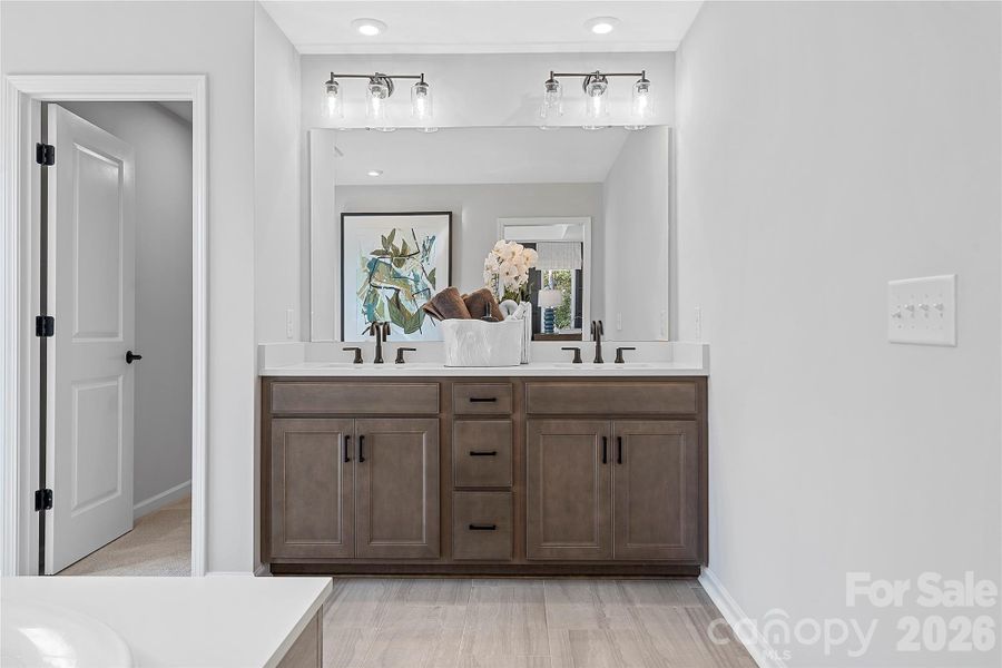 En suite primary bath with modern wood toned cabinetry. En suite primary bath with modern wood toned cabinetry.