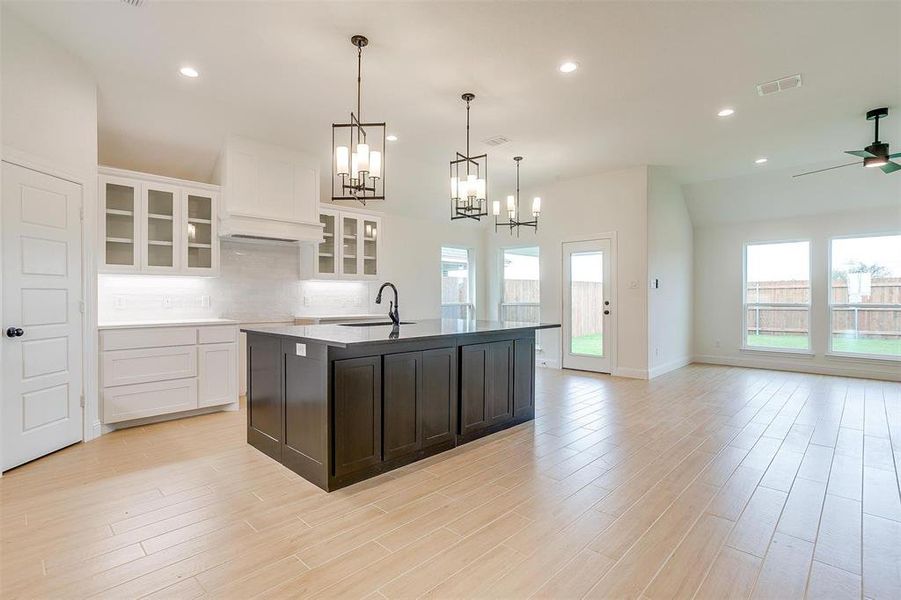 Kitchen featuring an island with sink, white cabinets, sink, and light hardwood / wood-style floors