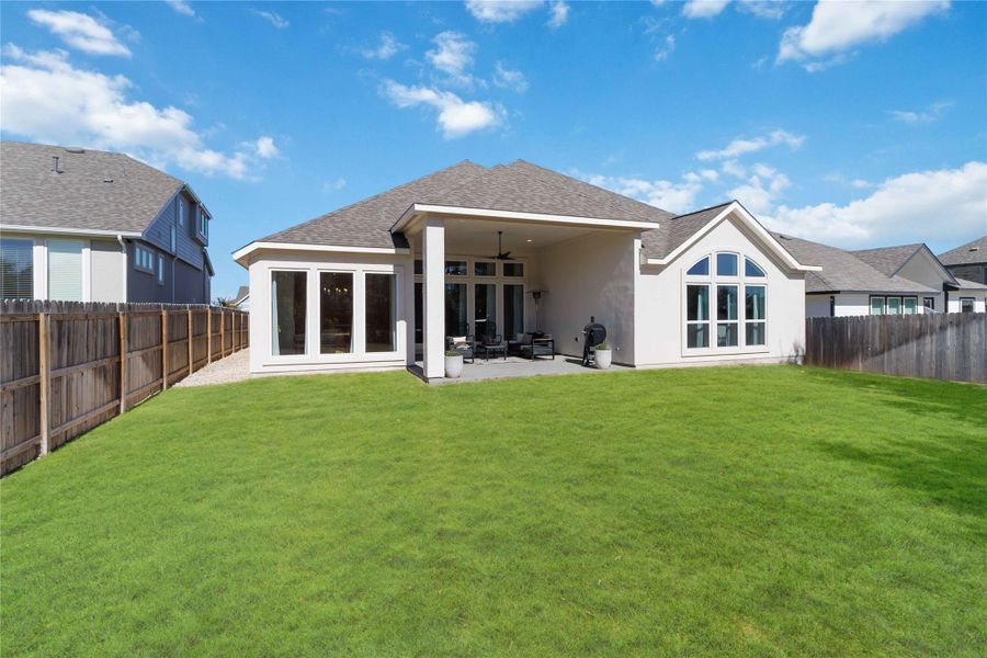 Rear view of house with roof with shingles, a patio area, a fenced backyard, a ceiling fan, and stucco siding Rear view of house with roof with shingles, a patio area, a fenced backyard, a ceiling fan, and stucco siding