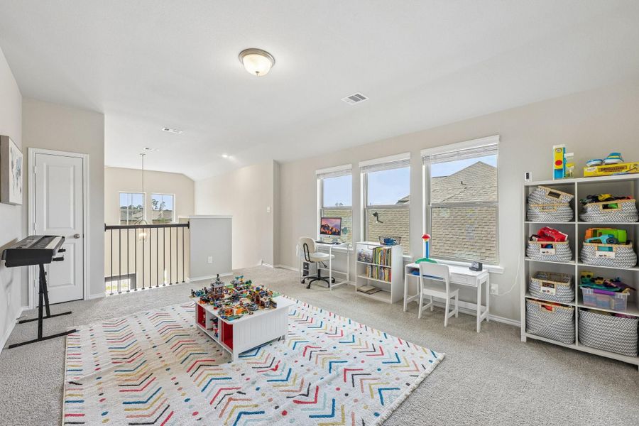 Bright and spacious loft area perfect for a playroom or home office, featuring large windows, ample storage, and a cozy carpeted floor.