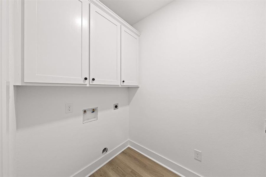 Laundry area featuring cabinet space, light wood-type flooring, washer hookup, and electric dryer hookup