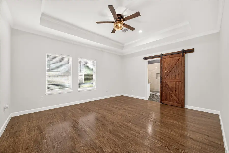 Generously sized primary bedroom with beautiful natural light and warm flooring.
