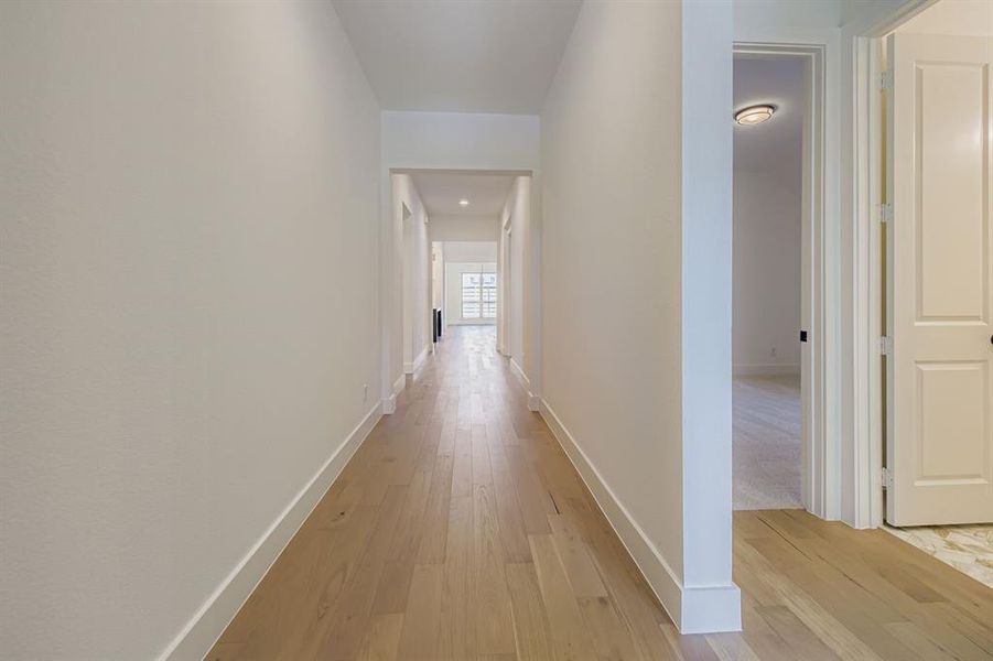 Corridor featuring light wood-style flooring and baseboards Corridor featuring light wood-style flooring and baseboards