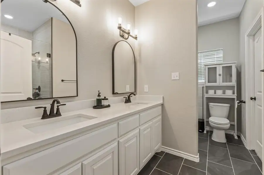 Primary bath featuring double vanity, dark tile patterned flooring, a textured wall, and recessed lighting Primary bath featuring double vanity, dark tile patterned flooring, a textured wall, and recessed lighting
