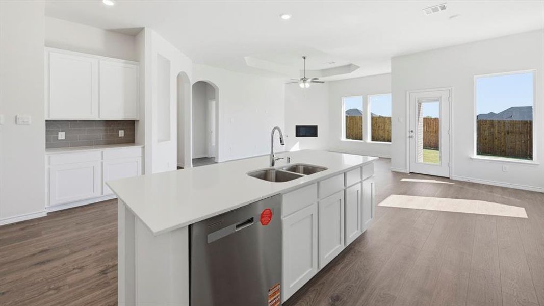 Kitchen with white cabinetry, dishwasher, arched walkways, a tray ceiling, and dark wood-type flooring