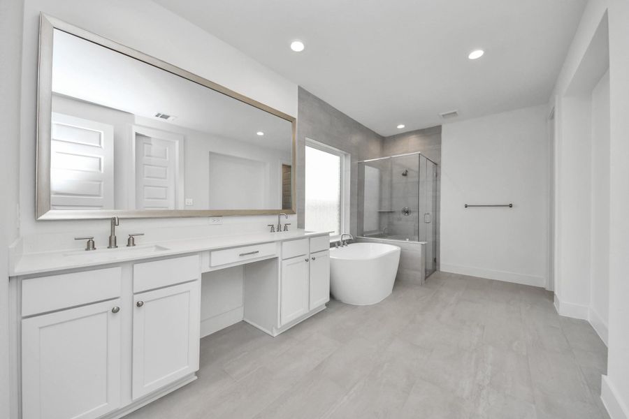 Elevate your daily routine at the elegant vanity, now equipped with double sinks, light countertops, modern hardware, and beautiful recessed lights.