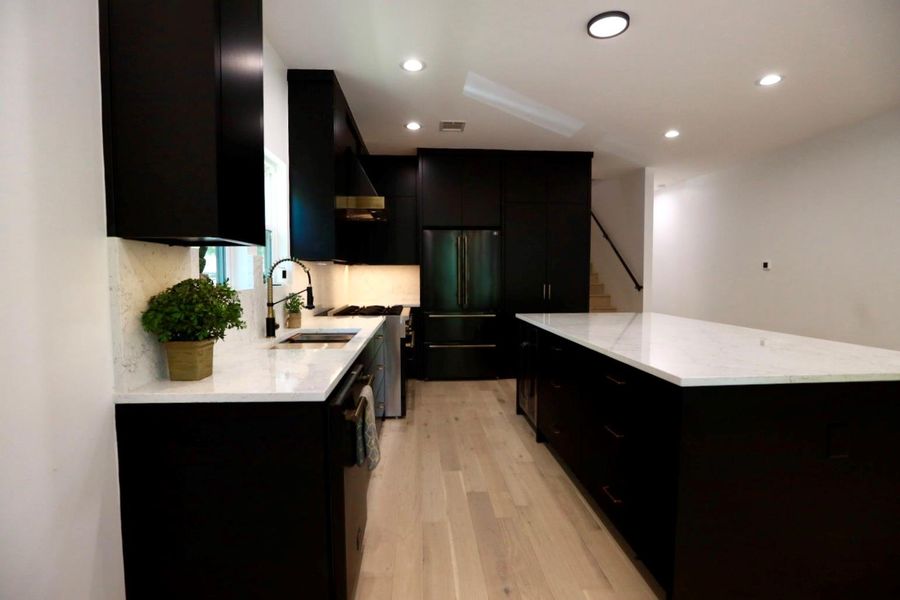 Kitchen featuring dark cabinets, a kitchen island, freestanding refrigerator, light wood finished floors, and recessed lighting