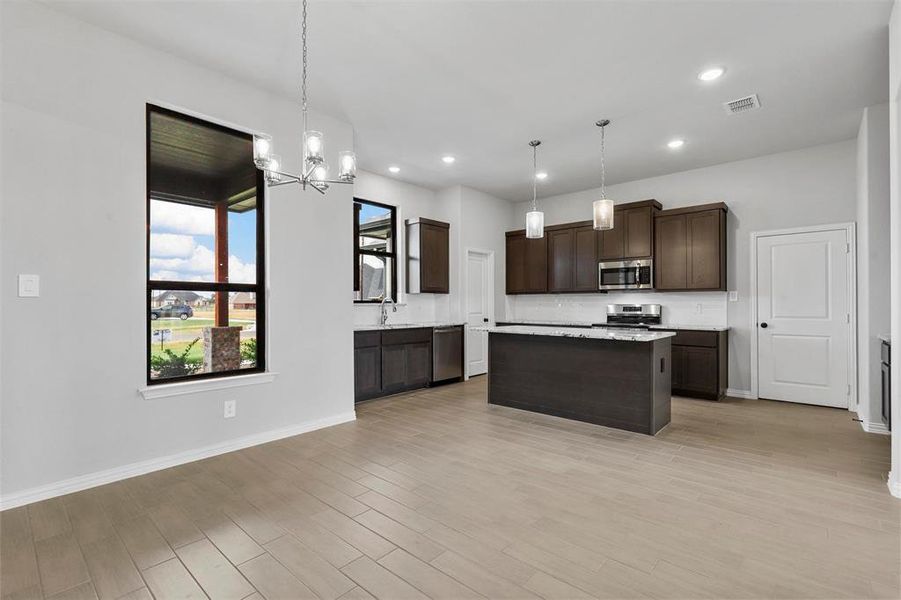 Kitchen featuring hanging light fixtures, light wood-type flooring, sink, a kitchen island, and appliances with stainless steel finishes