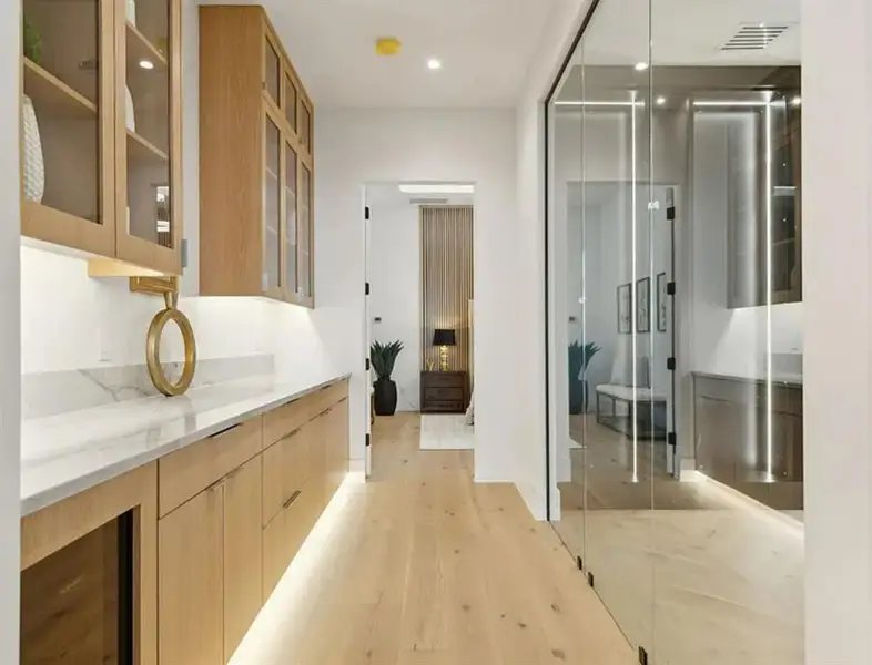Bar area featuring light stone counters, light wood finished floors, recessed lighting, modern cabinets, and glass insert cabinets