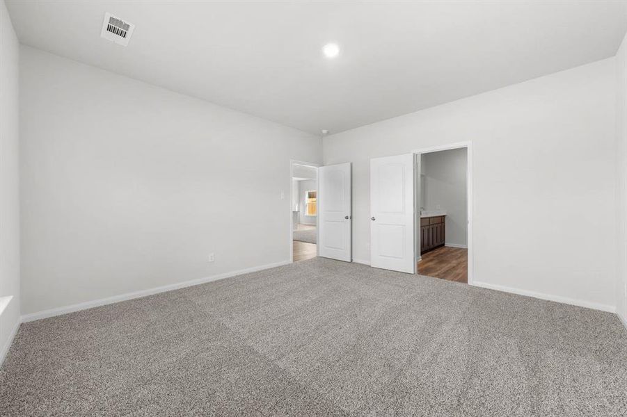 Unfurnished bedroom featuring ensuite bathroom and carpet flooring