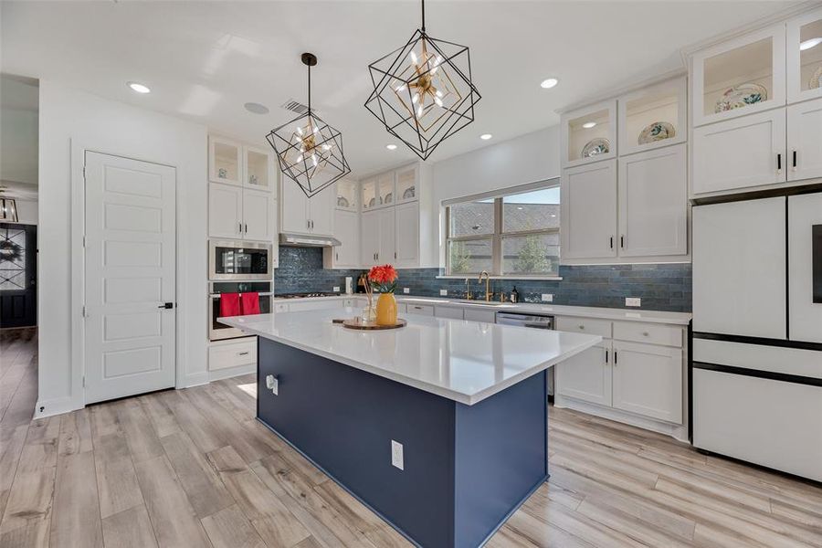 Kitchen featuring white cabinetry, appliances with stainless steel finishes, hanging light fixtures, a kitchen island, and recessed lighting