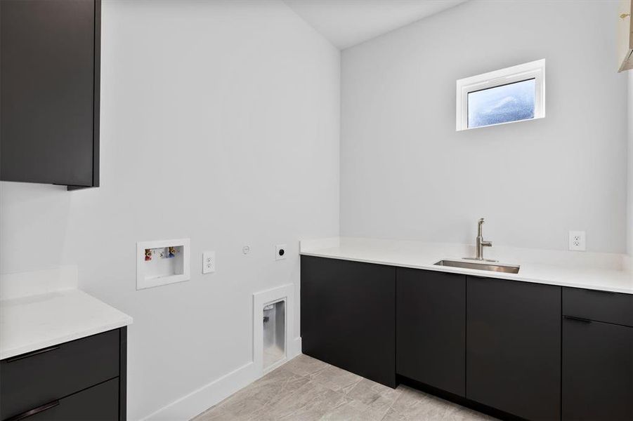 Washroom featuring cabinets, washer hookup, hookup for an electric dryer, gas dryer hookup, and sink